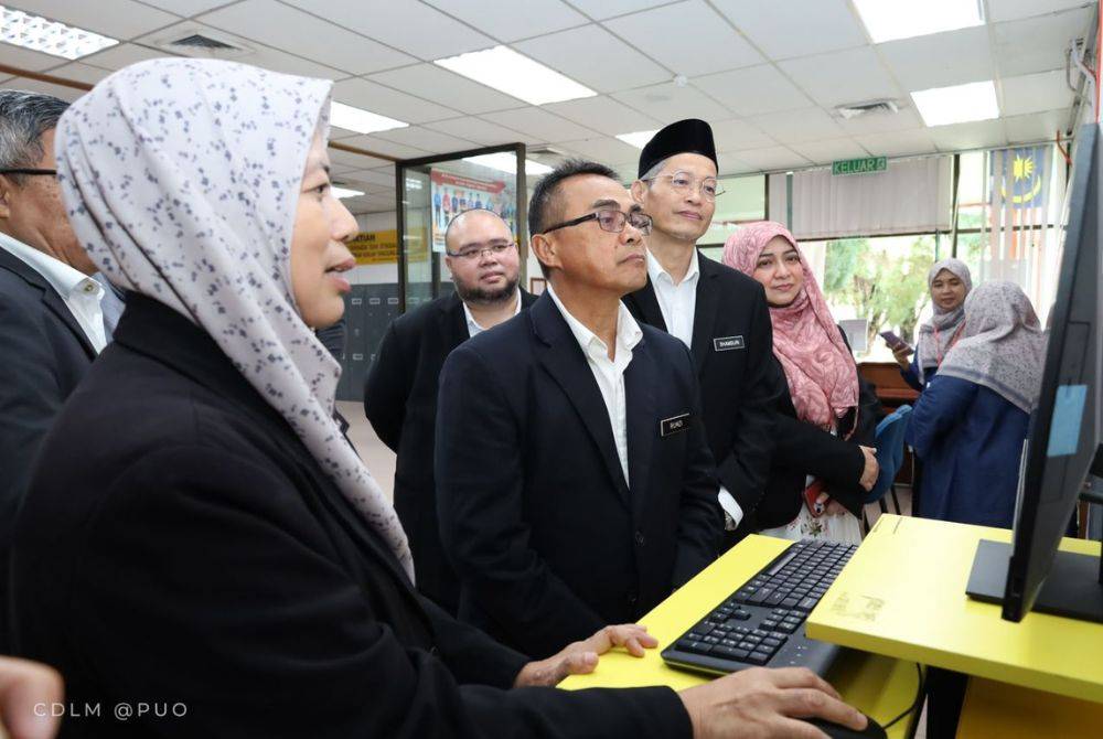 Muhamad Rumzi (tengah) melihat sistem yang dilancarkan di Perpustakaan Tan Sri Othman Merican, Politeknik Ungku Omar, Ipoh, Perak.