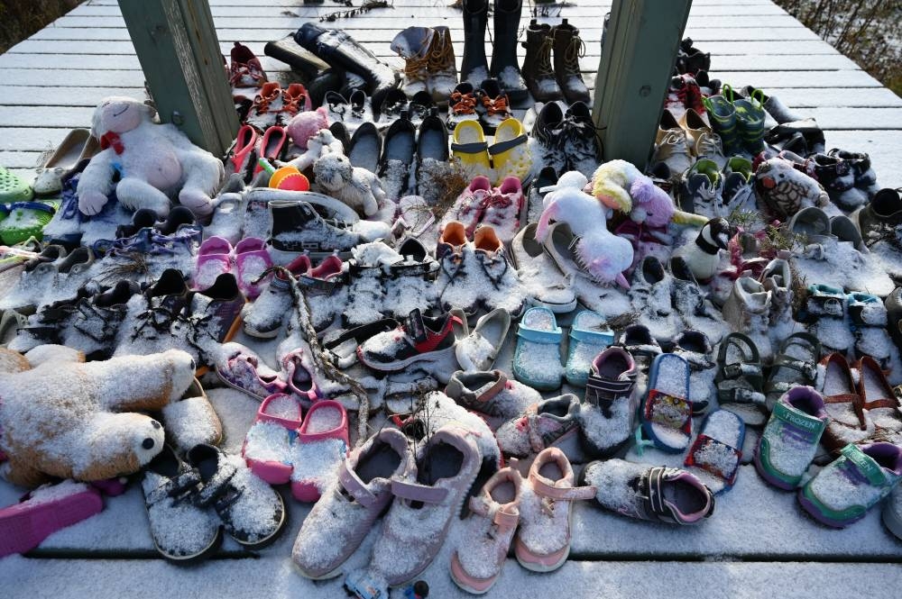 Children's shoes adorn a memorial for Saint-Marc-de-Figuery residential school student at the site of the former school near Amos, Canada, Nov 17, 2021. (Photo by Marion THIBAUT / AFP)