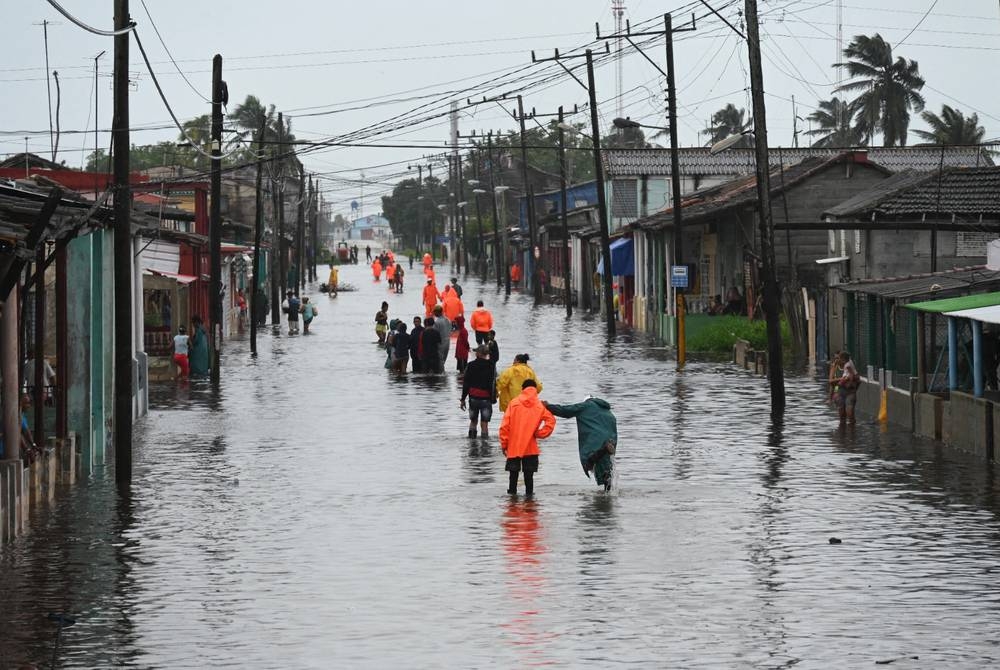 TOPSHOT - People walk through a flooded street in Batabano, Mayabeque province, Cuba on Aug 29, 2023, during the passage of tropical storm Idalia. (Photo by Yamil LAGE / AFP)