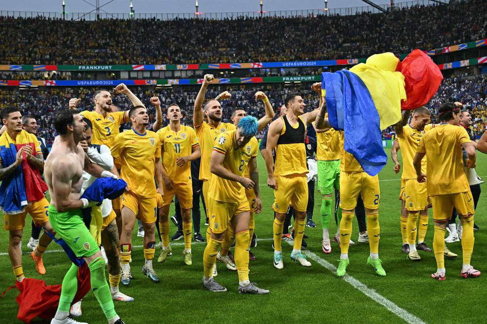 Hráči Rumunska oslavujú víťazstvo v skupine na ihrisku po futbalovom zápase skupiny E Euro 2024 medzi Slovenskom a Rumunskom vo Frankfurtskej aréne vo Frankfurte nad Mohanom.  Fotografiu Javier Soriano/AFP