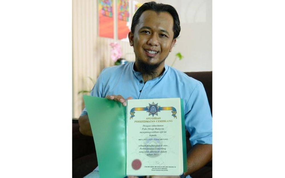 Saiful Bahari menunjukkan sijil Anugerah Perkhidmatan Cemerlang 2013 yang diterimanya. - FOTO MOHD HALIM ABDUL WAHID