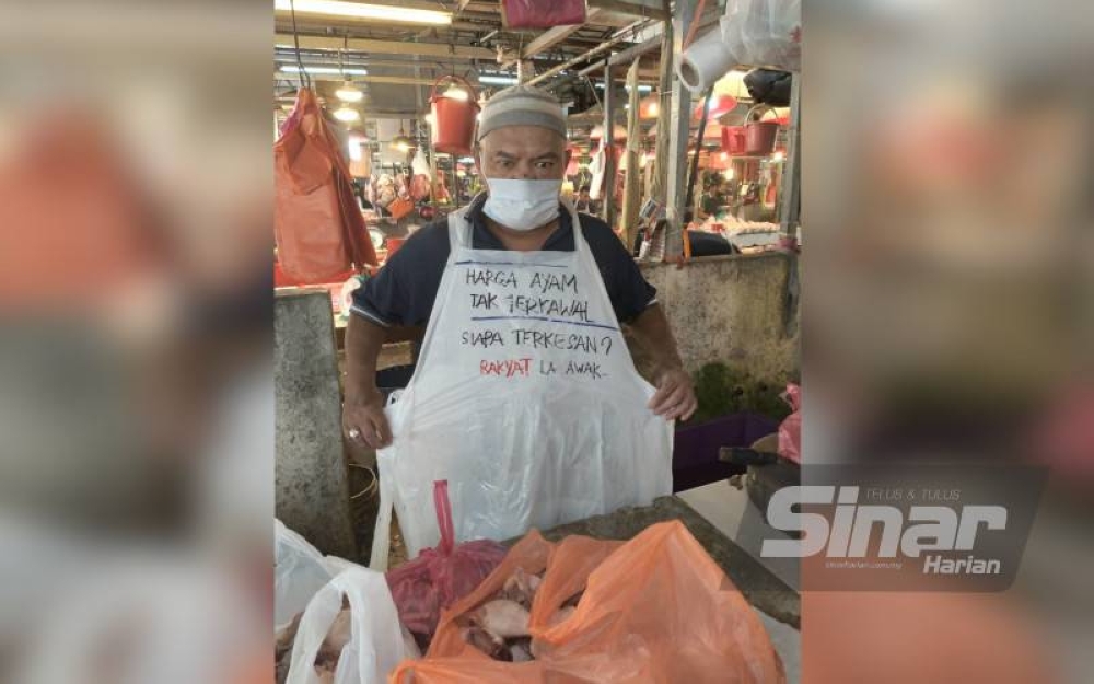 Seorang peniaga ayam di Pasar Chow Kit memakai apron yang ditulis berkenaan harga ayam tidak terkawal.