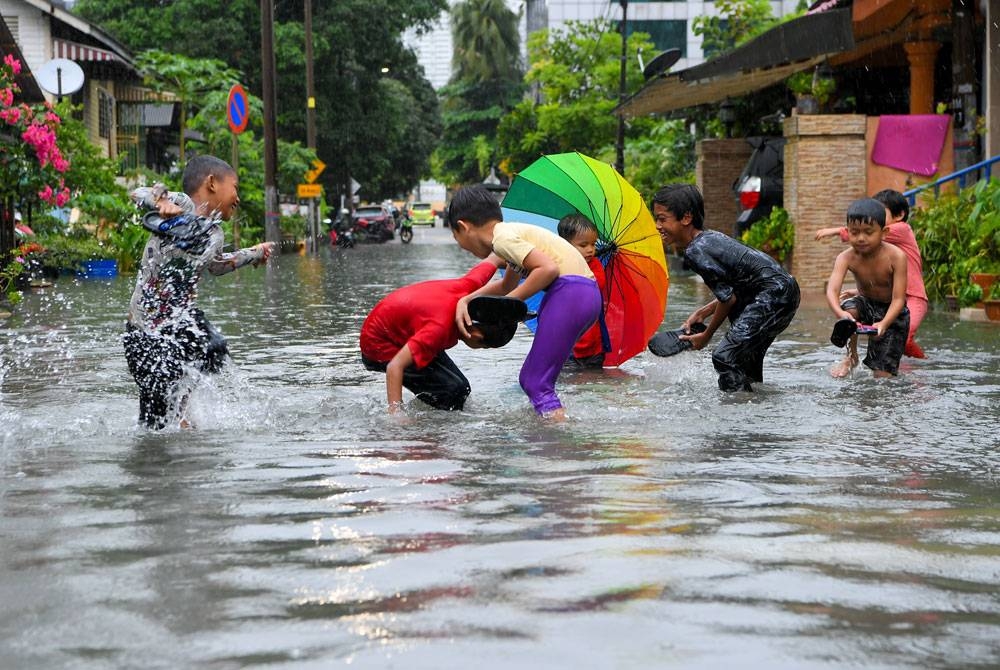 Sekali sekala berlaku banjir kecil. Seronoknya tidak terkata apabila dapat mengharung air. Lebih seronok lagi menyepak-nyepak air itu ke arah kawan-kawan. -Foto Bernama