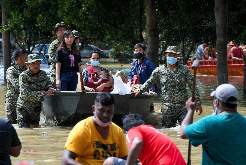 Beberapa anggota Angkatan Tentera Malaysia (ATM) membantu membawa keluar mangsa-mangsa banjir menggunakan bot ketika tinjauan di Taman Seri Muda Seksyen 25 pada Selasa. - Foto Bernama