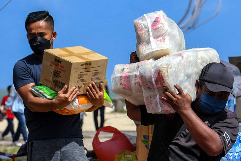 Sukarelawan NGO bawa barang keperluan sebelum diagihkan kepada mangsa-mangsa terjejas banjir di pusat pengumpulan bantuan banjir di Pantai Batu Burok 25 Disember lalu. - Foto Bernama