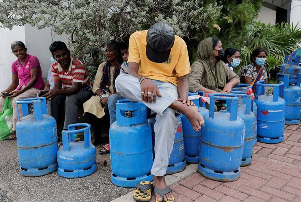 Seorang lelaki duduk di atas tong gas silinder ketika menunggu barisan untuk membeli gas di jalan utama, di tengah-tengah krisis ekonomi negara di Colombo, Sri Lanka. - Foto AFP