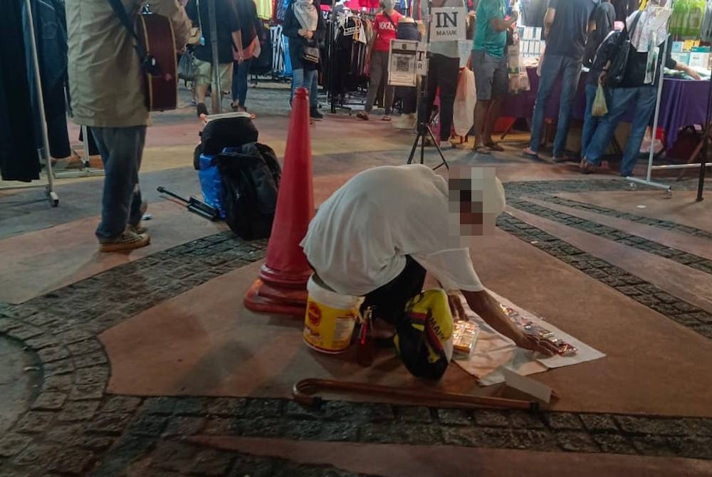 Seorang lelaki mengemis di hadapan sebuah bank di Pusat Perdagangan Greentown, Ipoh.