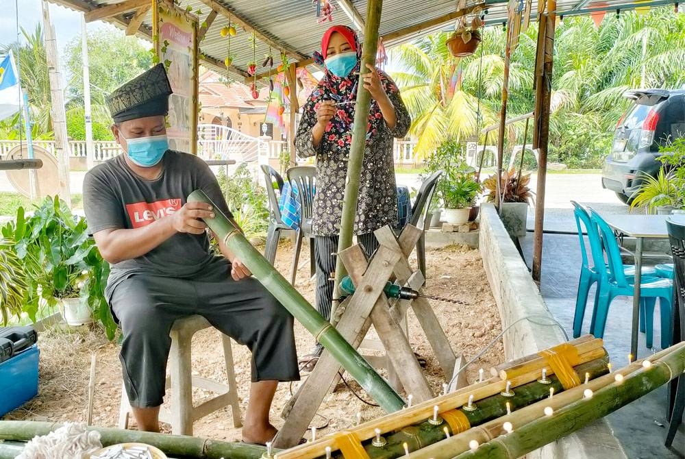 Kamisah (dua dari kiri) membantu suaminya, Nazri menyiapkan tempahan pelita buluh.