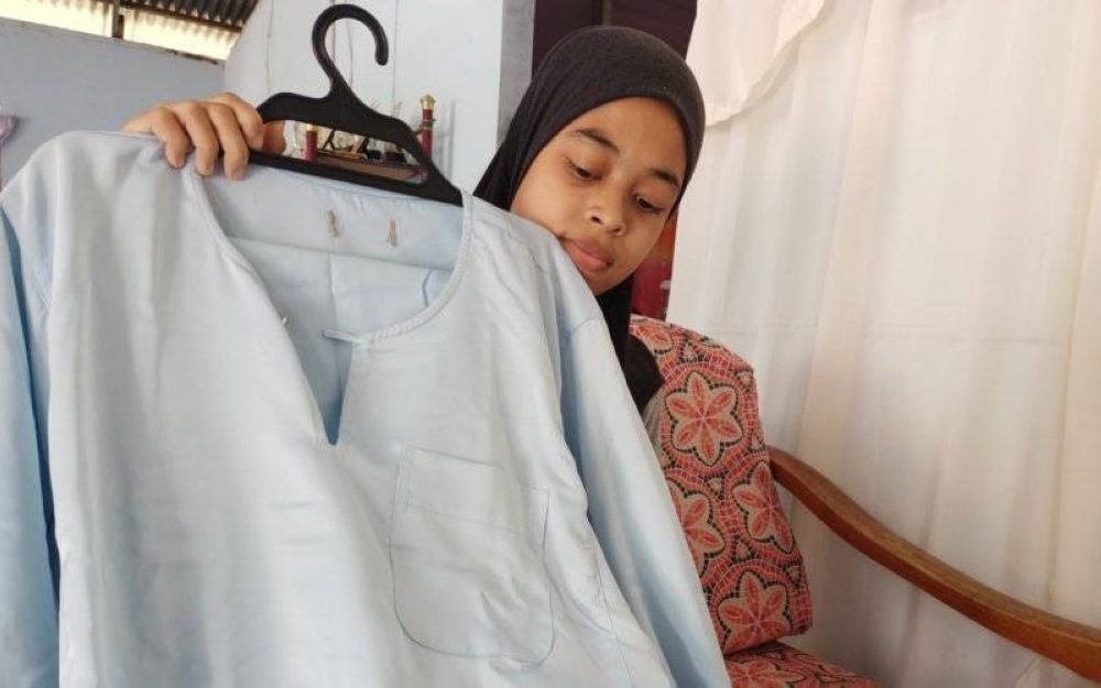 Nor Aina menunjukkan baju Melayu berwarna biru cerah yang dibelikan mereka untuk Firdaus sempena Aidilfitri ini.