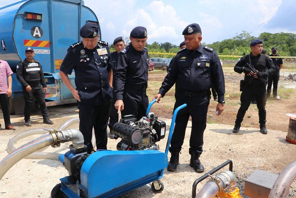 Kamarul Zaman (depan, kanan) menunjukkan antara peralatan yang digunakan untuk kegiatan penyelewengan diesel.