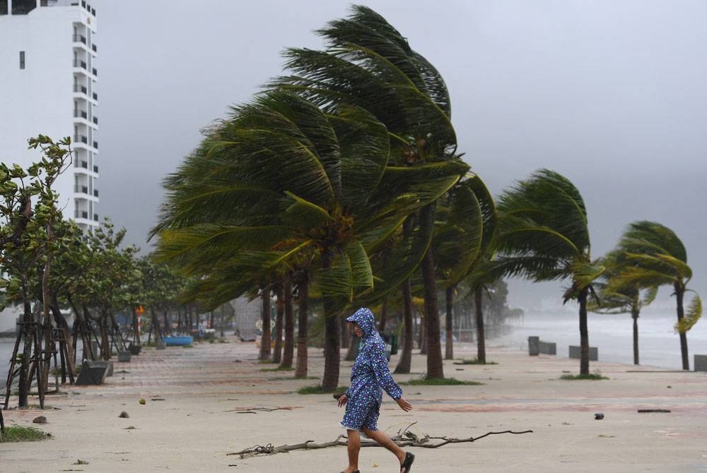 Seorang lelaki berjalan di pantai semasa Taufan Noru membadai Danang. - Foto AFP