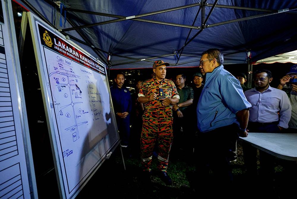 Abd Latiff (kanan) mendengar penerangan ketika melawat ke Pusat Kawalan Tempat Kejadian (PKTK) di Taman Sri Muda sebagai langkah persediaan menghadapi bencana banjir pada Selasa.