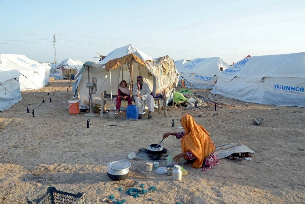 Seorang wanita memasak makanan untuk keluarganya yang ditempatkan di kem sementara di Sohbatpur di daerah Jaffarabad, wilayah Balochistan.