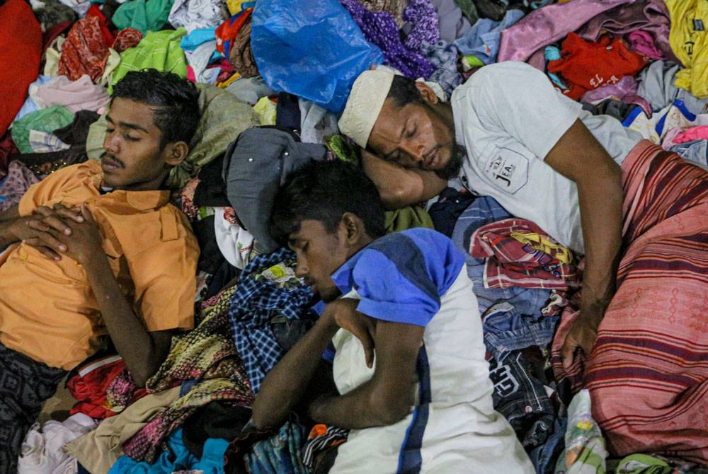 Pelarian Rohingya tidur di atas lambakan pakaian yang disumbangkan orang awam di sebuah pusat perlindungan di daerah Muara Tiga di Pidie.