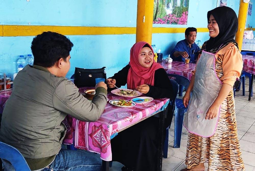 Maimunah (kanan) melayan pelanggan dari Malaysia yang singgah makan di kedainya di Dannok, Thailand.