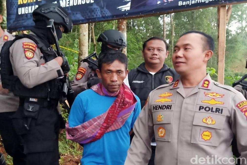 Mbah Slamet diiringi anggota polis ketika menunjukkan lokasi kesemua mayat mangsa yang ditanam di sebuah ladang.