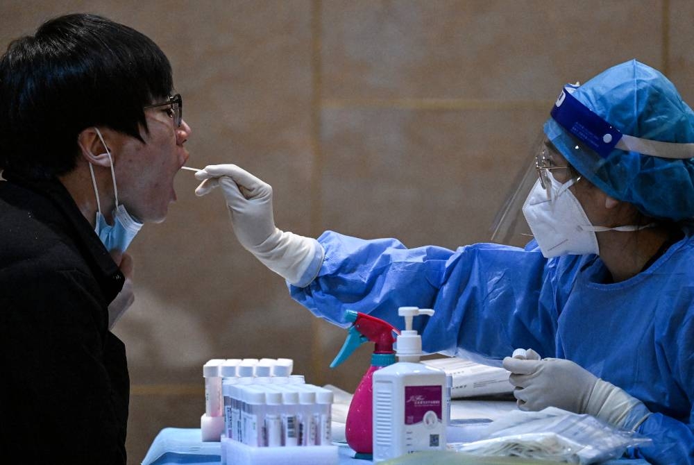 Petugas kesihatan mengambil sampel daripada individu untuk ujian Covid-19 di Beijing, China. - AFP