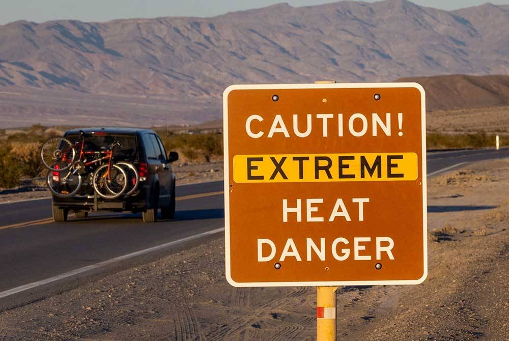 Papan tanda memaparkan amaran bahaya suhu panas melampau di tepi jalan di Furnace Creek, California.