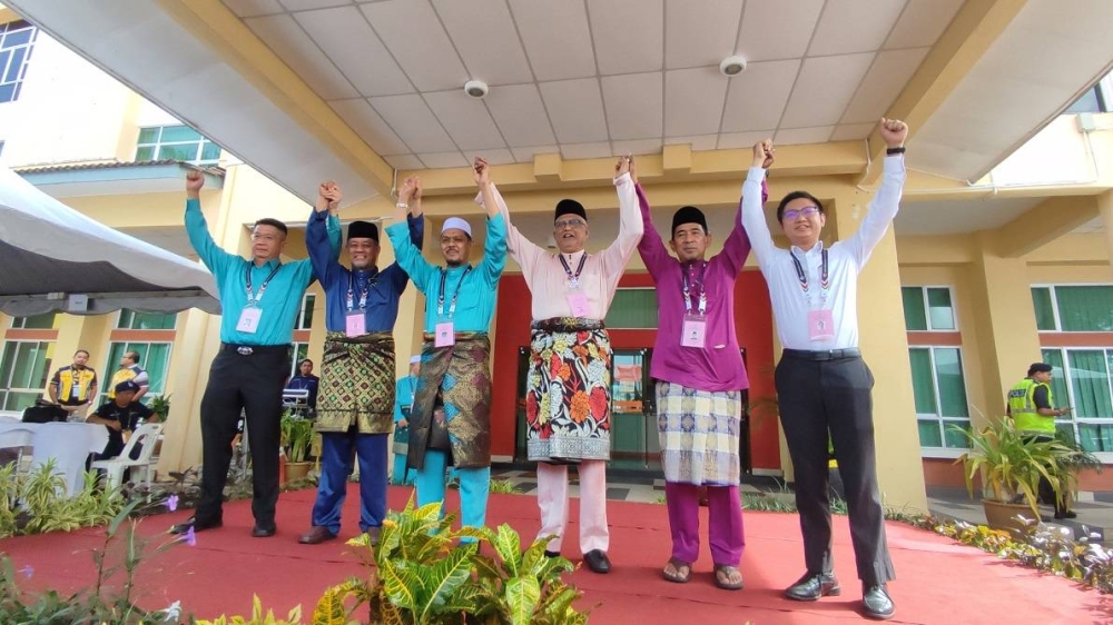 Mahfuz (tiga, kanan) dan Radhi (tiga, kiri) bersama calon Suka Menanti dan Kota Darulaman mengangkat tangan beramai-ramai selepas diumumkan sebagai calon di Pusat Penamaan Calon DUN di Kompleks Belia dan Sukan Negeri Kedah, di sini, pada Sabtu.