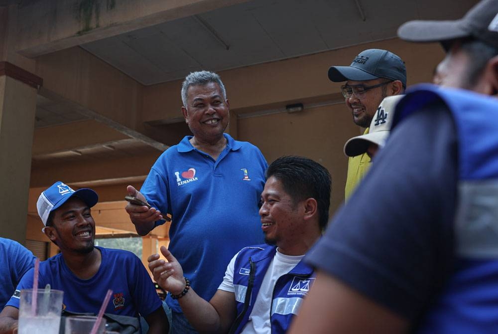 Ahmad (berdiri, kiri) bersama ahli dan jentera parti ketika program beramah mesra bersama penduduk setempat di Pantai Teluk Kalong Kijal.