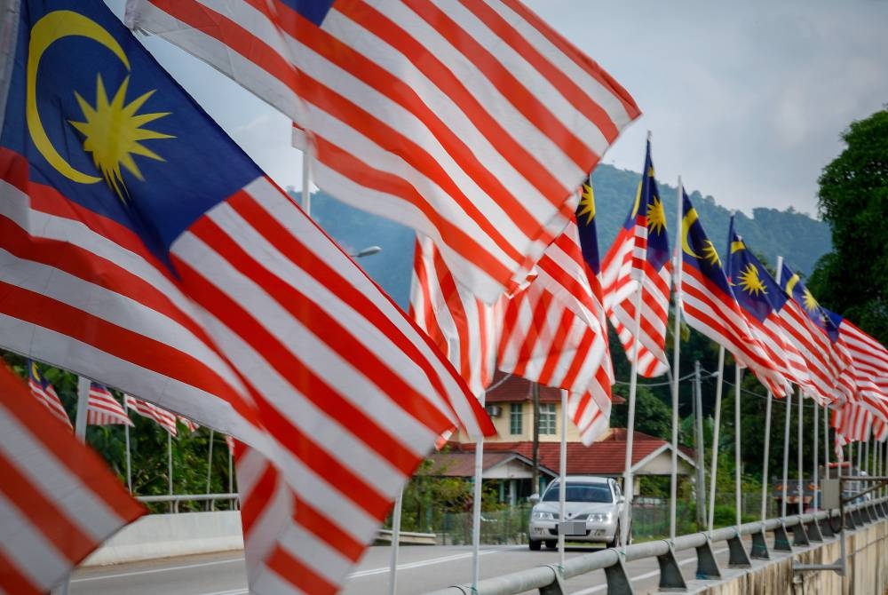 Pengguna jalan raya melintasi deretan Jalur Gemilang yang dipasang bagi memeriahkan sambutan Hari Kebangsaan. - Foto Bernama