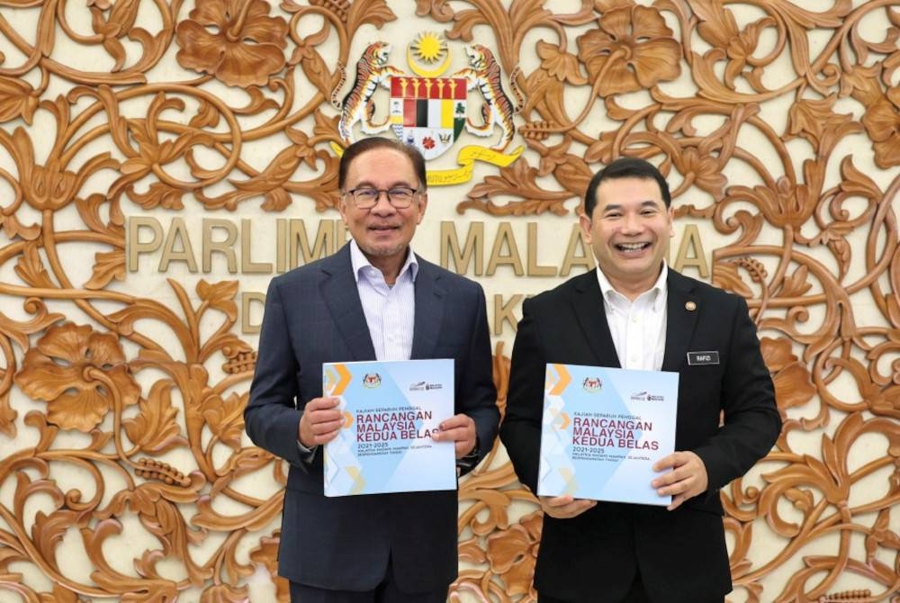 Anwar (kiri) bersama Menteri Ekonomi, Rafizi Ramli menunjukkan buku Kajian Separuh Penggal (KSP) RMK12 bertemakan ‘Malaysia Madani: Mampan, Sejahtera, Berpendapatan Tinggi’ pada Mesyuarat Khas Dewan Rakyat. - Foto Bernama