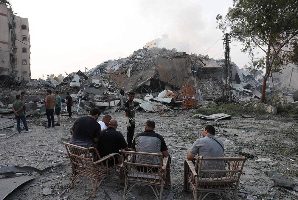 Beberapa penduduk Palestin berkumpul pada Ahad di hadapan runtuhan Menara Al-Watan Kota Gaza, yang musnah dalam serangan udara Israel. - Foto AFP