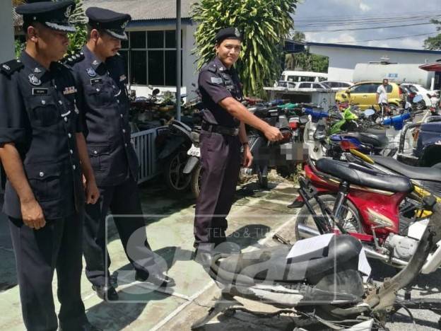 Suzaimi (kiri) bersama pegawainya menunjukkan motosikal yang dirampas