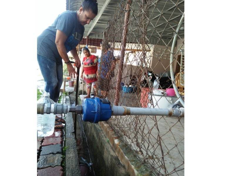 Salah seorang penduduk mengambil air di hadapan rumah seorang peniaga di Taman Minang hari ini. - Foto Bernama
