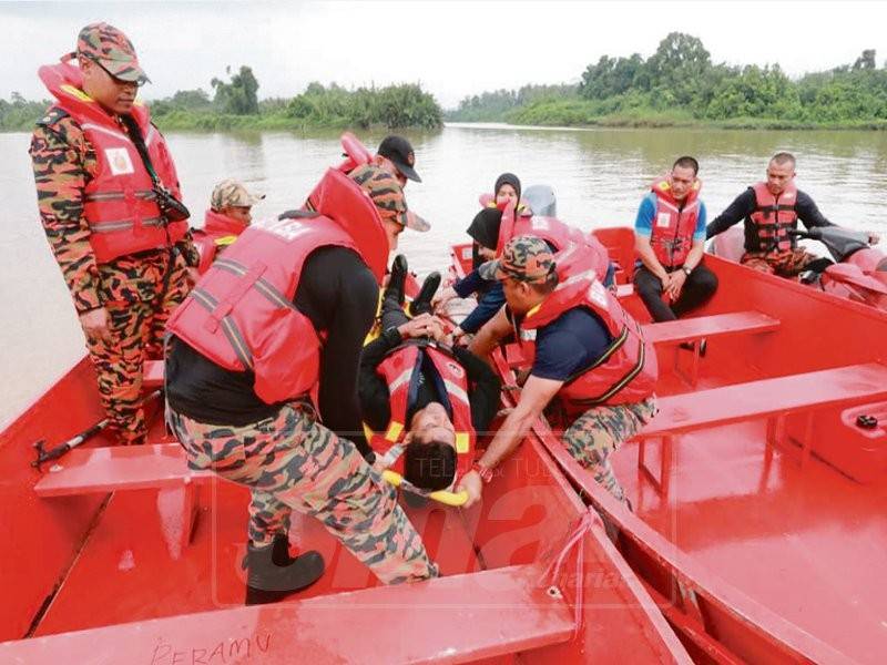 Mohd Ismail (kiri) mengajar anggotanya kaedah menyelamat mangsa banjir dari bot ke bot di Sungai Pahang, semalam
