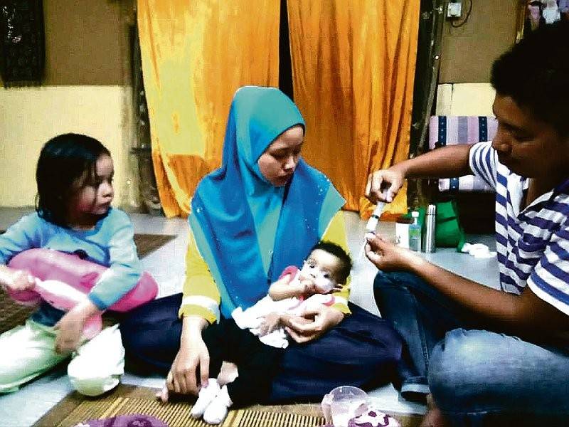 Nurul Wahidah (tengah) memangku Nurul Firzanah sambil Mohammad Feroz (kanan) memberi susu menggunakan picagari dan tiub khas.