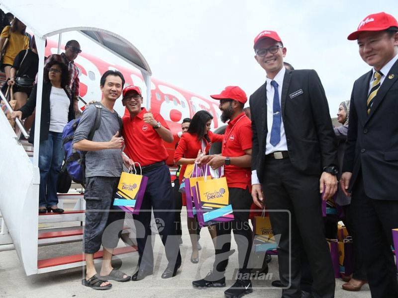 Ahmad Faizal menyambut salah seorang penumpang yang memulakan perkhidmatan pertama AirAsia Singapura-Ipoh di LTSAS, hari ini.