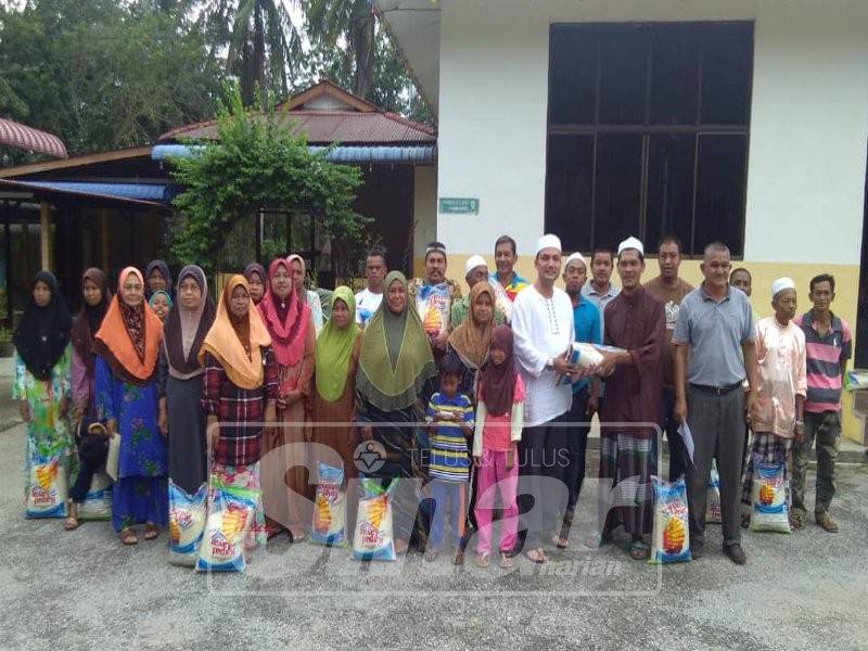 Ahmad Zulkifli (lapan, kanan) menyerahkan sumbangan beras kepada penoreh getah di Keda Bukit Kura, Kuala Nerang.