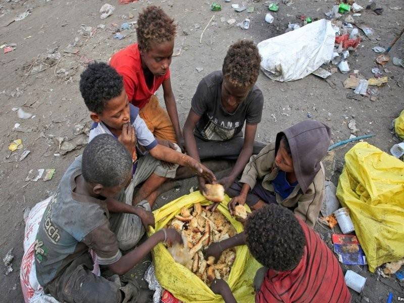 Kanak-kanak memakan roti yang dikutip dari tempat pembuangan sampah berhampiran bandar pelabuhan Hudaidah. - Foto Voanews.com 