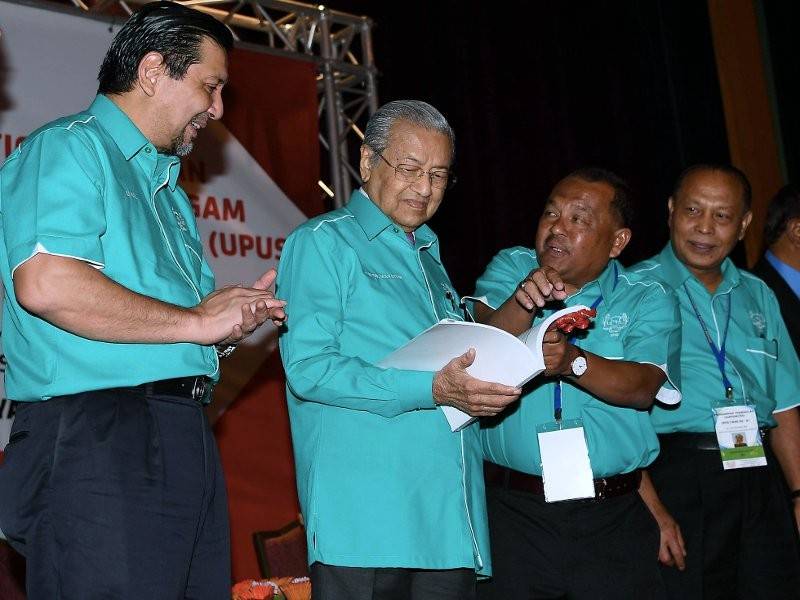 Perdana Menteri Tun Dr Mahathir Mohamad (dua, kiri) meneliti Buku Laporan Tiga Tahunan 2015-2018 selepas merasmikan Persidangan Perwakilan Kesatuan Pekerja-Pekerja Pakaian Seragam Pos Malaysia Berhad Semenanjung Malaysia (UPUS) ke-21, hari ini. - Foto Berna