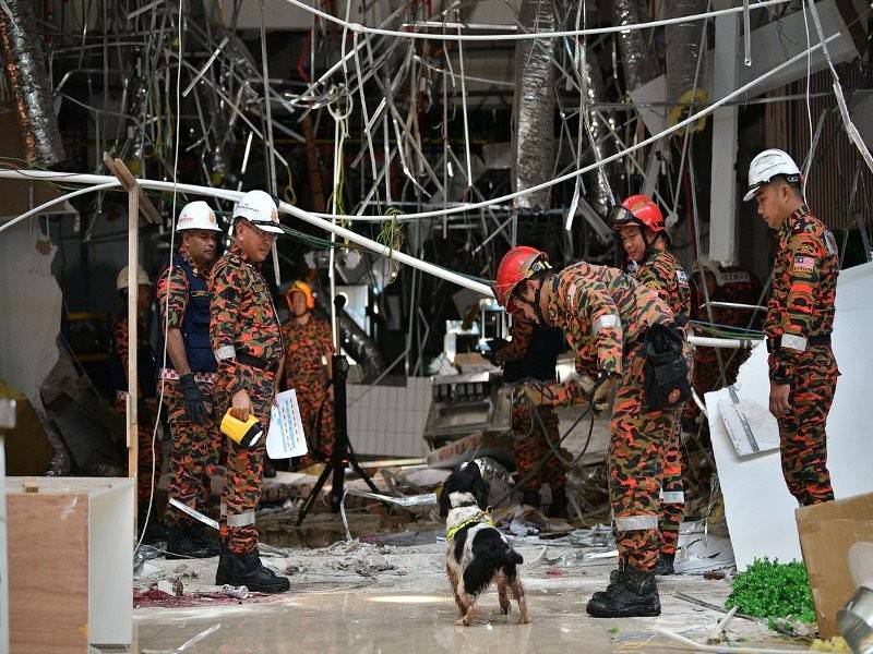 Anggota Bomba dan Penyelamat Sarawak menggunakan anjing pengesan untuk menyiasat punca letupan di pusat membeli- belah CityOne Megamall hari ini. - Foto Bernama
