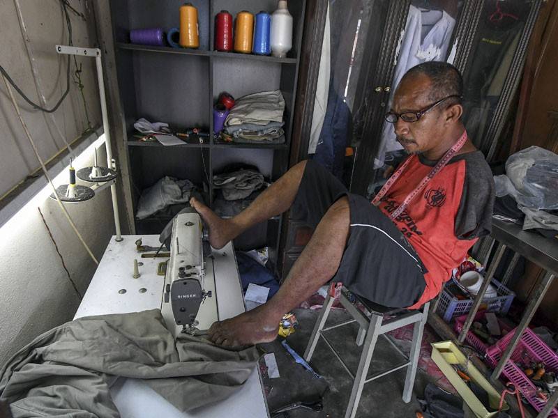 Pok Su Mie sedang menyiapkan pakaian yang dipesan oleh pelanggan di kedai jahitnya yang terletak di Pulai Chondong di sini. - Foto Bernama