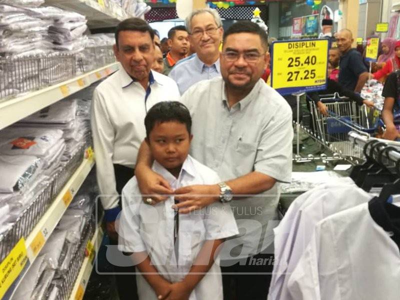 Mujahid (tengah) menyantuni salah seorang penerima bantuan untuk pakaian sekolah baharu sewaktu program sumbangan Back To School Parlimen Parit Buntar di Mydin Mall, hari ini.