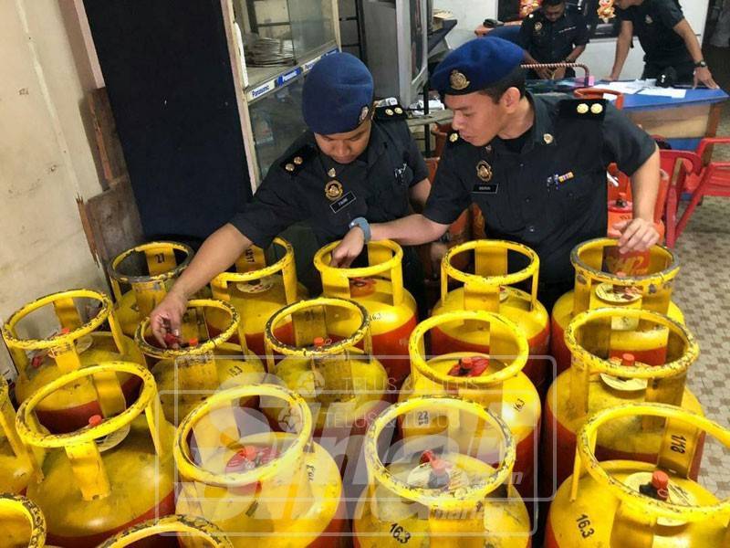 Pegawai KPDNKK memeriksa tong LPG yang disita dalam serbuan ke atas premis tersebut.