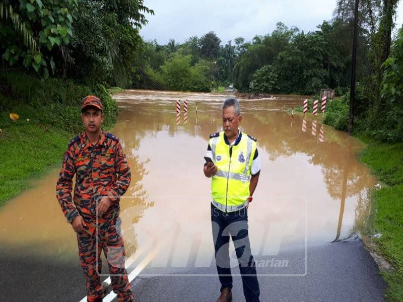 Mohd Said (kanan) meninjau Jambatan Teladas di Kampung Air Putih yang telah ditenggalami air, petang ini.