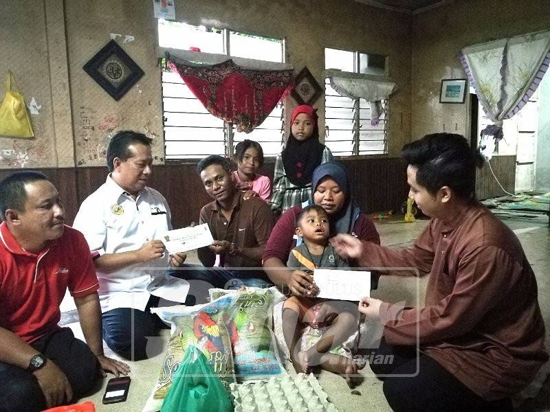 Zulkepli (dua, kiri) bersama wakil Tabung Beras 8 Asnaf (kanan) menyampaikan sumbangan kepada Arina sekeluarga.