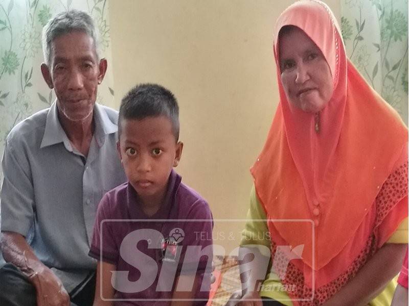 Syukri (tengah) bersama ibu bapanya di rumah mereka di Kampung Tanjung Piai.