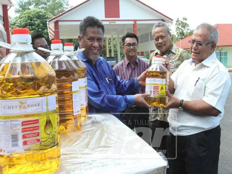 Mokhtar (kanan) menyerahkan minyak masak kepada Mohd Zafri pada majlis penyerahan bantuan minyak masak Kosma kepada JKM Pahang dipekarangan depot simpanan keperluan bencana negeri di Indera Mahkota.