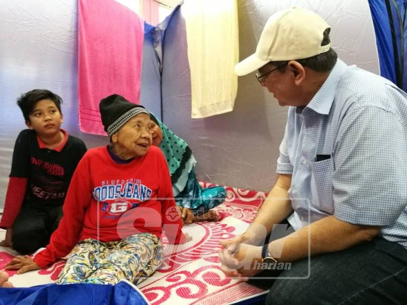 Saifuddin beramah mesra bersama seorang mangsa banjir, Munah Khamis yang ditemui di Pusat Pemindahan Sementara (PPS) SK Sungai Karang di sini, hari ini.