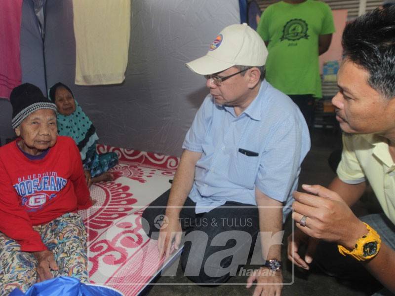 Saifuddin (dua, kanan) beramah mesra bersama Munah selepas menerima lawatan Saifuddin di Pusat Pemindahan Sementara (PPS) Sekolah Kebangsaan (SK) Sungai Karang di sini, hari ini.
