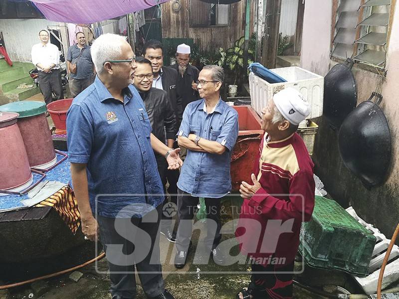 Mahfuz (kiri) menziarahi penjual ikan semasa menjejaki asnaf untuk agihkan zakat wakalah di Kampung Kedai Geting.