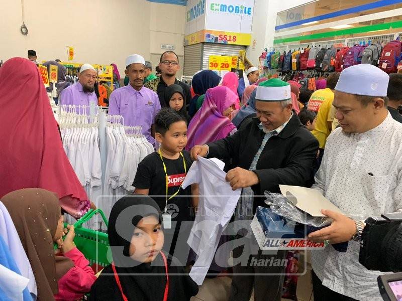 Tuan Ibrahim (dua, kanan) melayan kanak-kanak, Mohamad Aidid Muhriz mencuba pakaian semasa Majlis Back To School di sini.