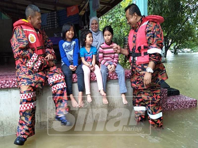 Ani bersama anak dan cucunya mendengar penerangan daripada pihak bomba berhubung keadaa cuaca terkini di rumahnya di Kampung Jeram Perdah.