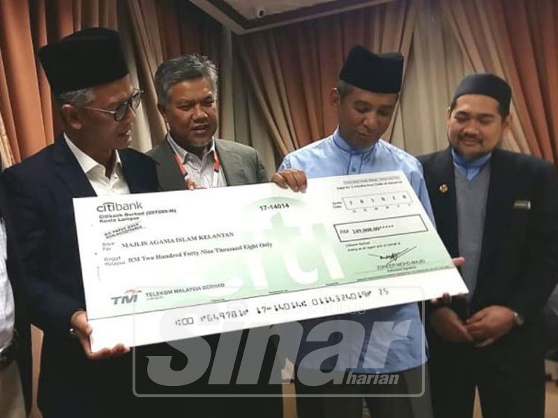 Azman (dua kiri) menyampaikan replika cek zakat kepada Nik Mohd Azlan.