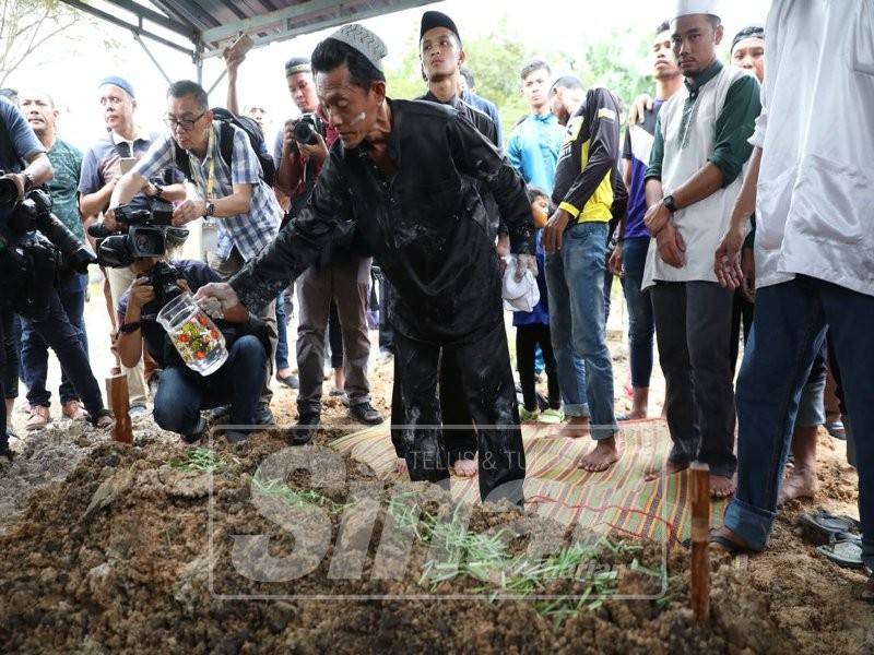 Nor Azman menyiram air di pusara anaknya.